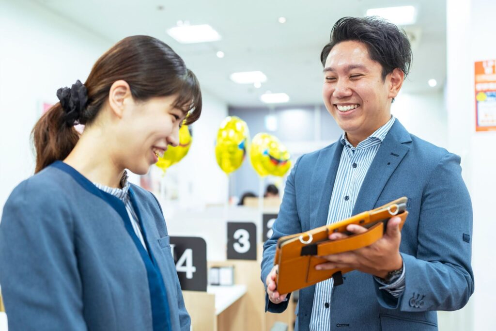 ハイコムグループの携帯ショップで働く女性とiPadで指導する男性